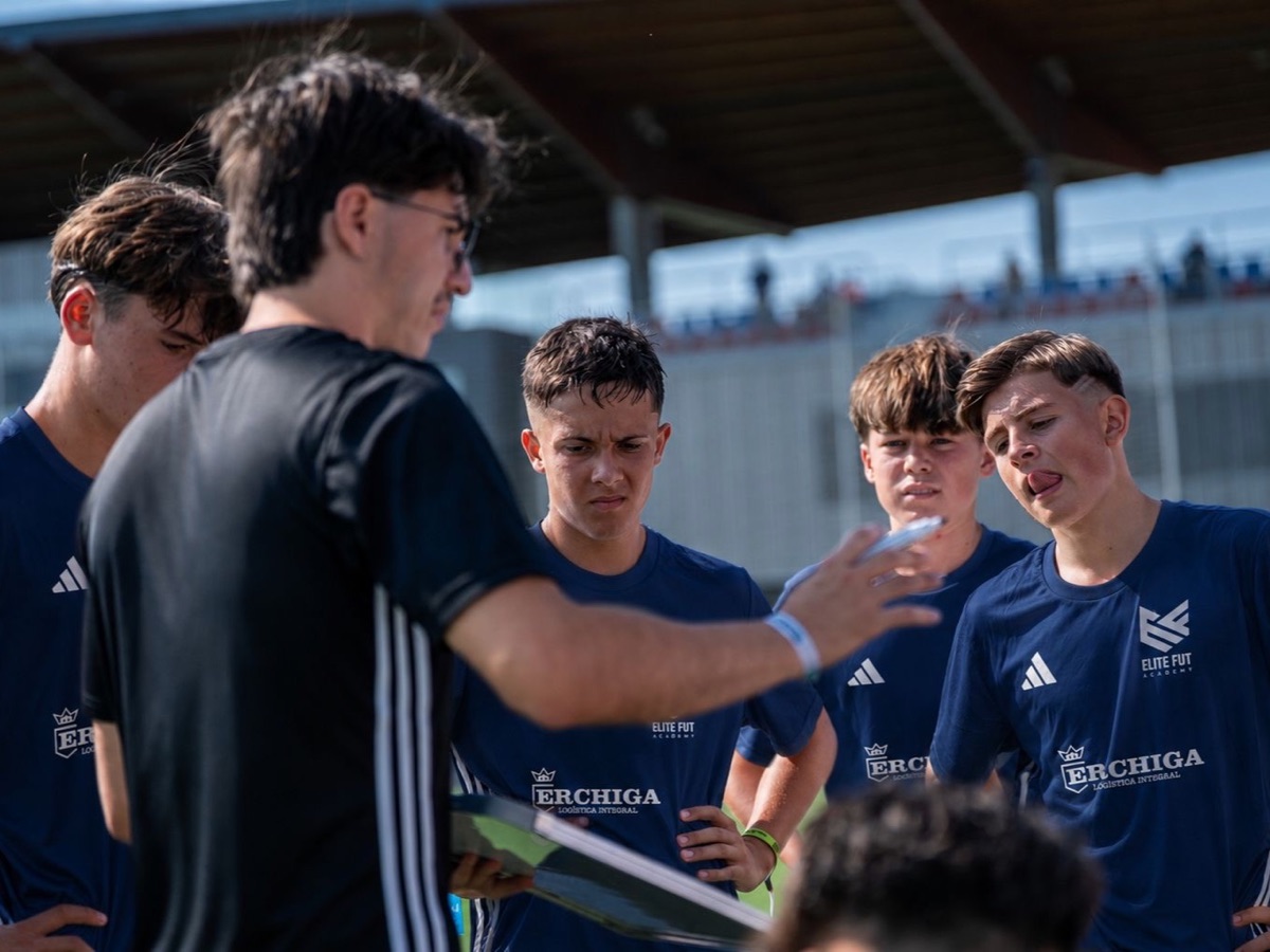 Entrenador explicando en la pizarra a un grupo de jugadores de Elite Fut Academy